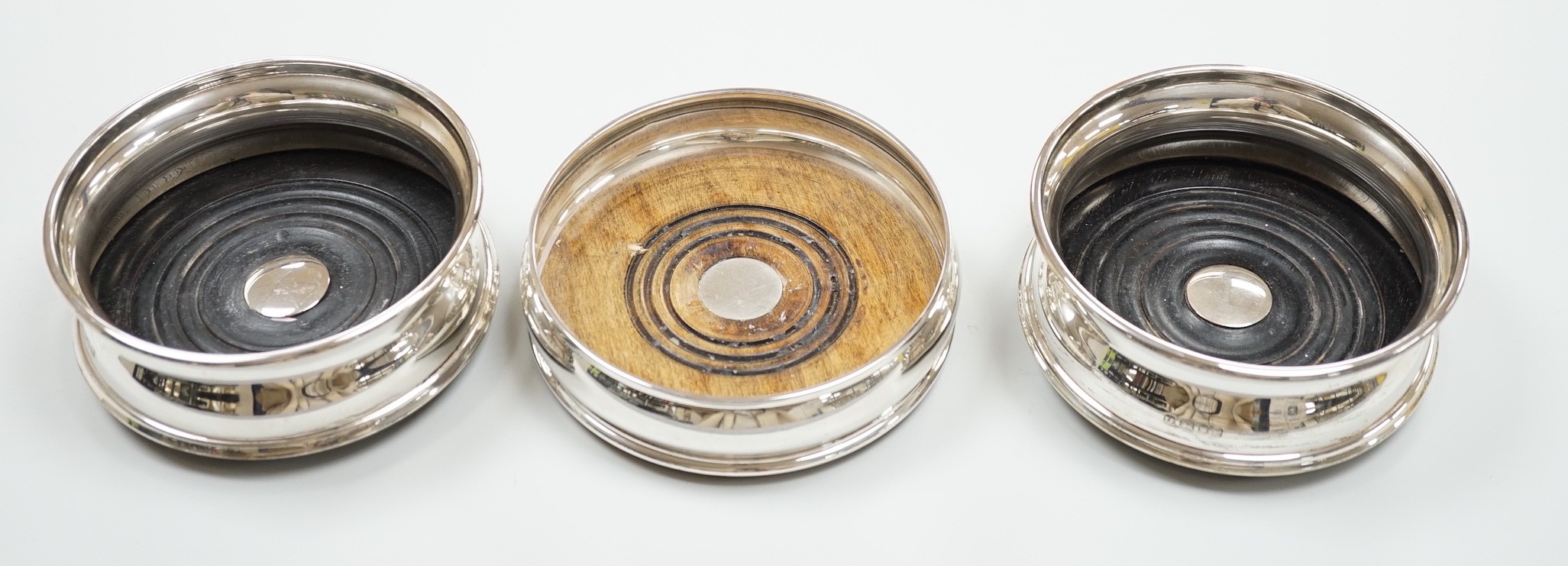 A pair of modern silver wine coasters, diameter 12.4cm and a single silver mounted wine coaster.